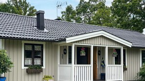 A single-story house with a porch, a chimney, and a flag. - 7 Person Holiday Home in Hagby (Ljungbyholm)