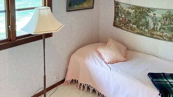 A bedroom with a bed, a lamp, a painting, and a window.