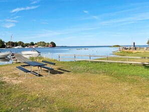 A lakeside view with a dock, boats, and a picnic area.