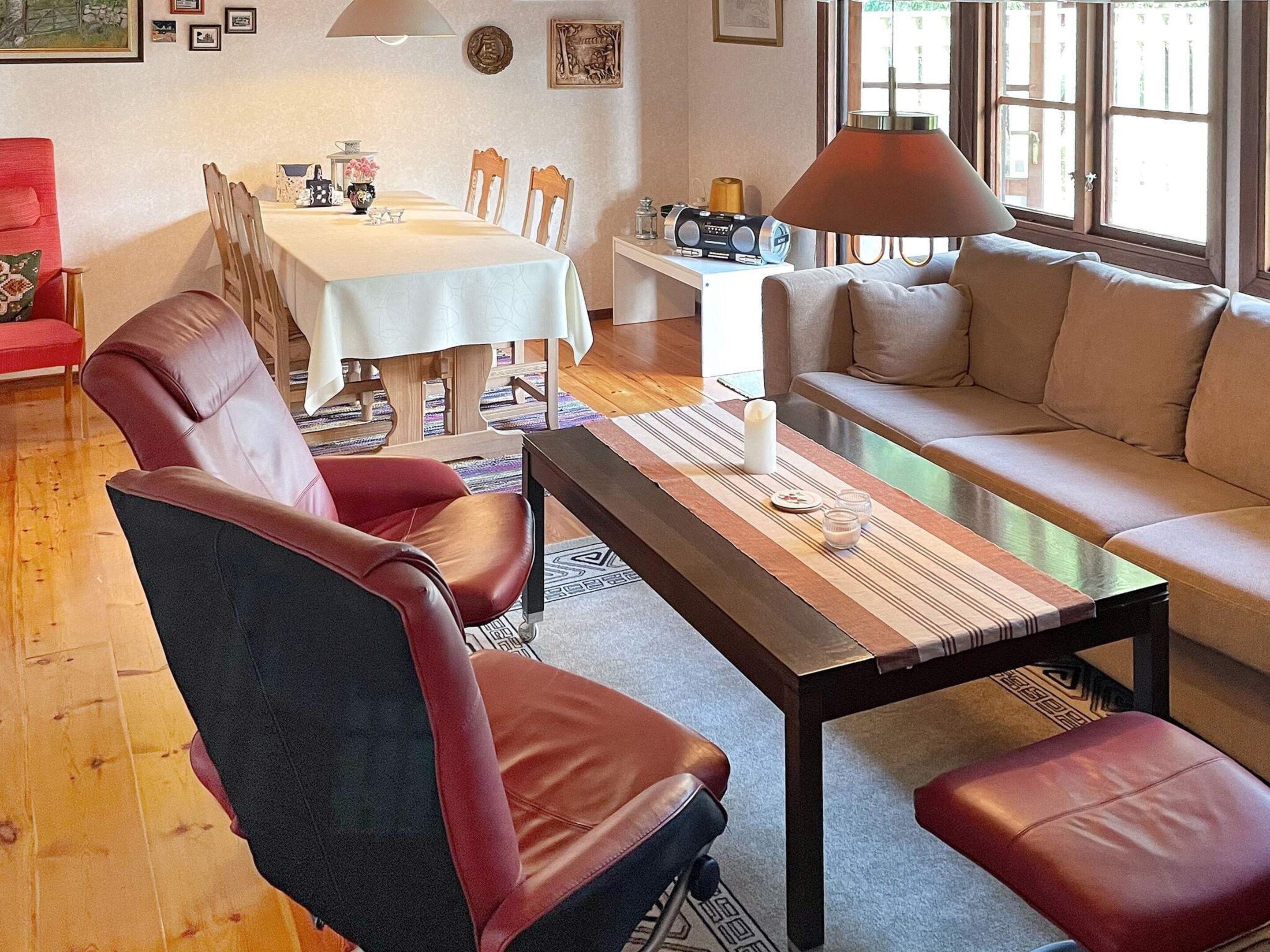 A living room with a sofa, a coffee table, and a dining area with a table and chairs.