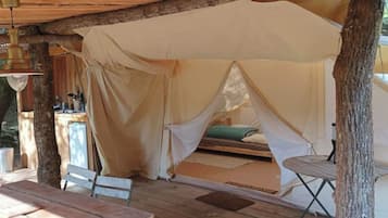 A tent with a canopy, a bench, and a table with a lantern.
