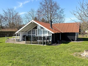 Une maison dotée d’une grande véranda, d’un garage et d’une pelouse bien entretenue.