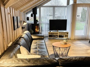 Uma sala de estar moderna com sofá de couro, televisão e lareira a lenha.