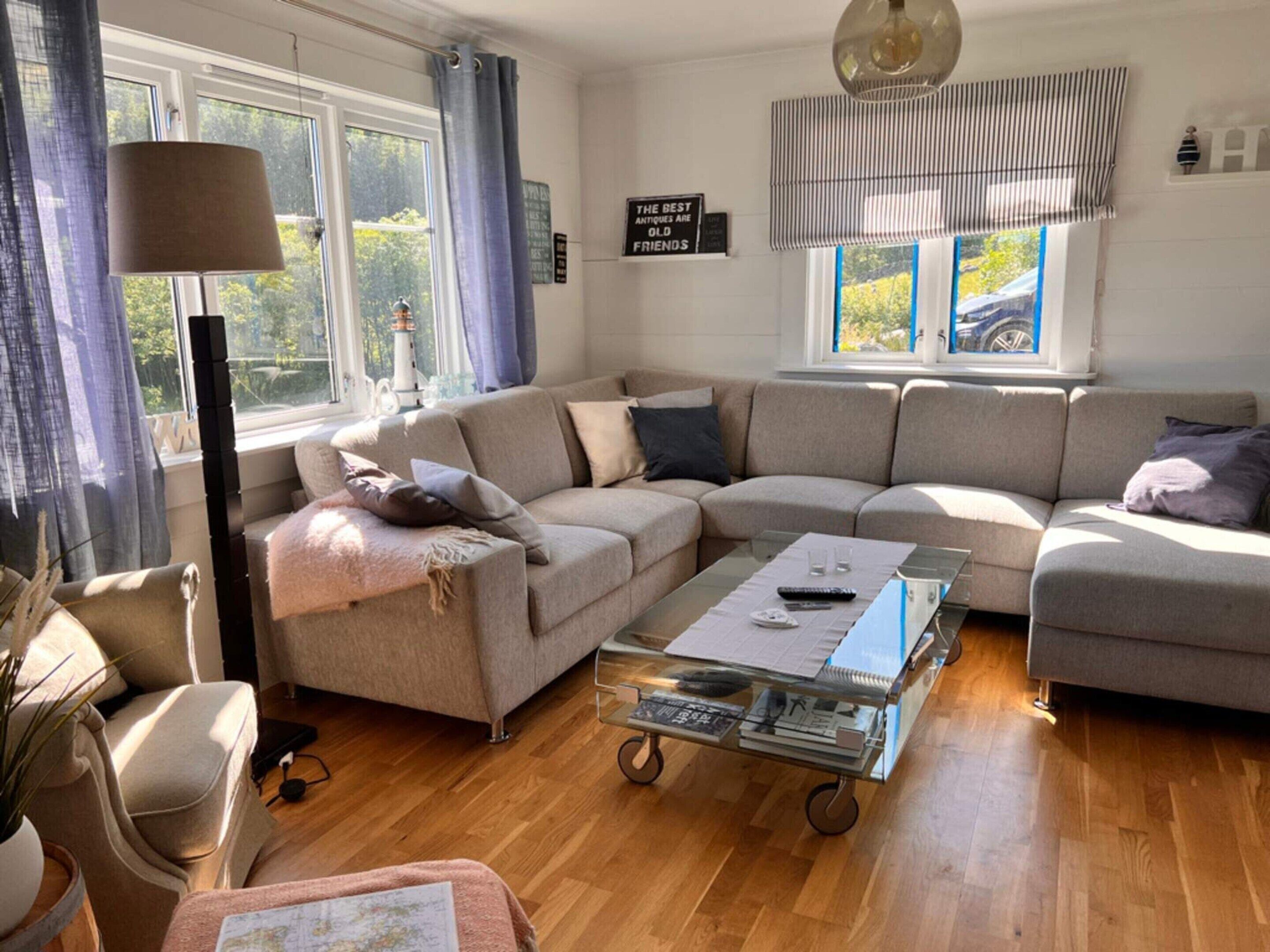 A modern living room with a sectional sofa, a glass coffee table, and a lamp.