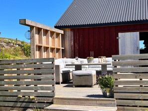 A wooden deck with outdoor furniture, a red barn, and a metal roof. - 8 Person Holiday Home in Nedstrand (Tysvaer)