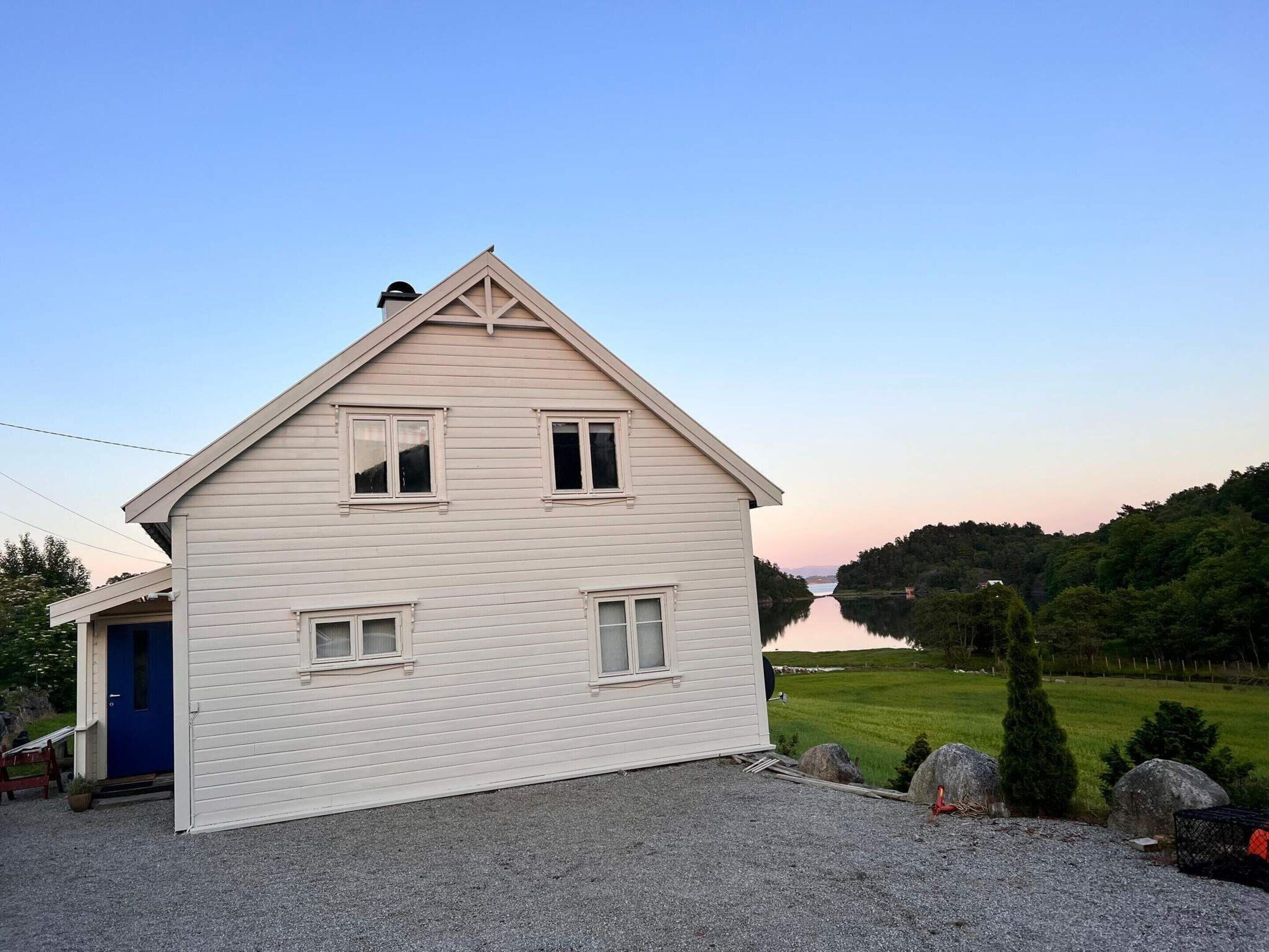 A two-story house with a gabled roof and a gravel driveway.