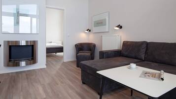 En moderne stue med et fladskærms-tv, en sofa, et sofabord og et billede i ramme på væggen.
