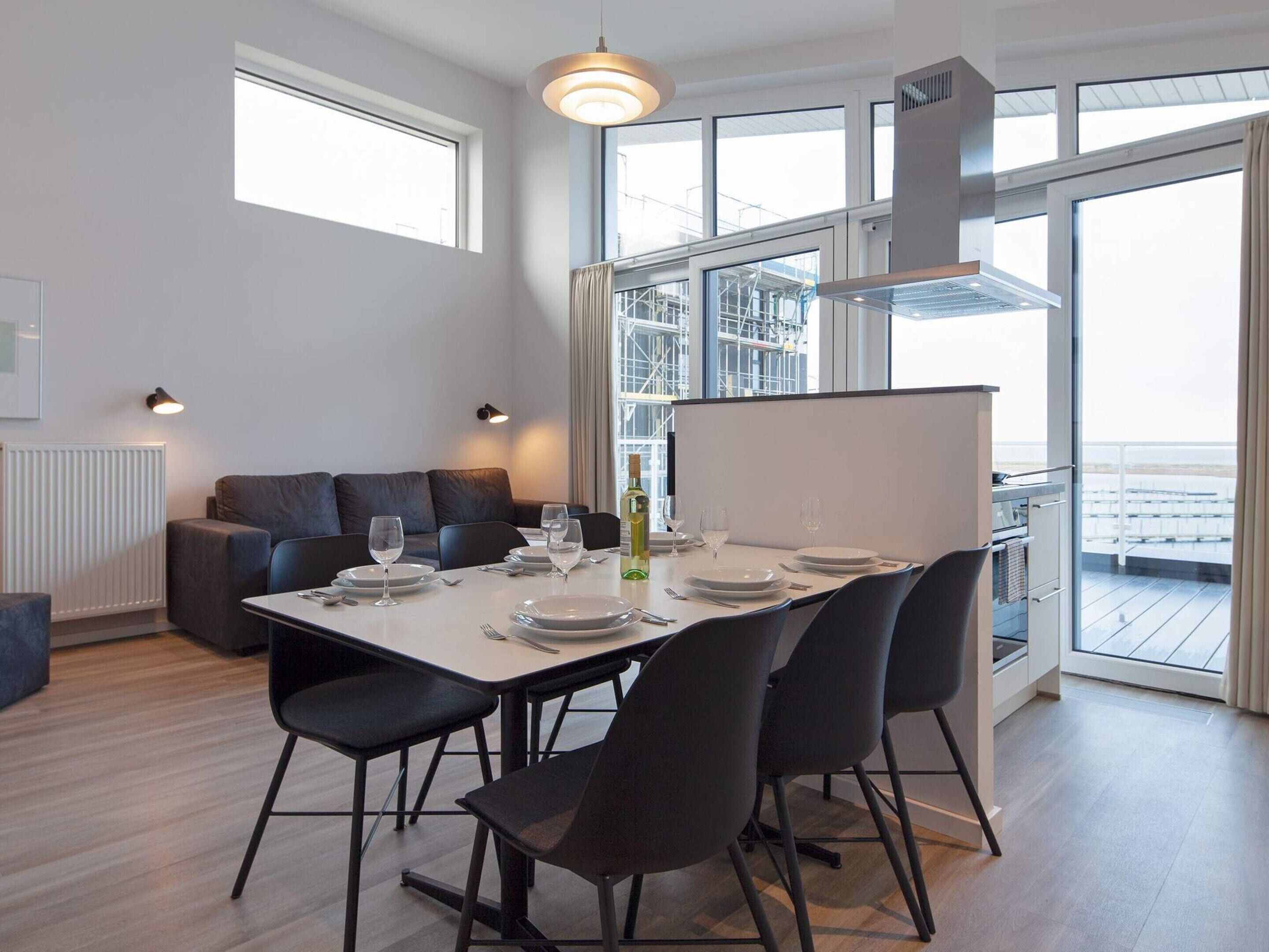Ein moderner Essbereich mit einem Tisch für vier Personen, einer Couch und Blick ins Freie.