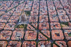 Une vue aérienne d’une zone urbaine densément peuplée, où l’on aperçoit un bâtiment remarquable qui se distingue par son architecture originale.