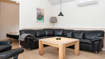 Una sala moderna con un sofá de cuero negro, una mesa de centro de madera y una silla negra.