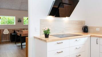 Una cocina moderna con encimera de madera, armarios blancos y extractor de aire negro.