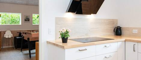A modern kitchen with a wooden countertop, white cabinets, and a black range hood.