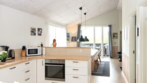 A modern kitchen with a central island, built-in oven, and a dining area with a view.