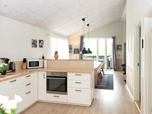 A modern kitchen with a central island, built-in oven, and a dining area with a view.
