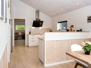 A modern kitchen with a central island, wooden cabinetry, and a built-in oven.