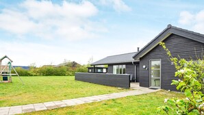 A modern house with a dark exterior, a paved driveway, and a grassy yard.
