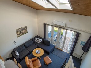 Una sala moderna con un sofá modular, una mesa de centro redonda y sillones de cuero.