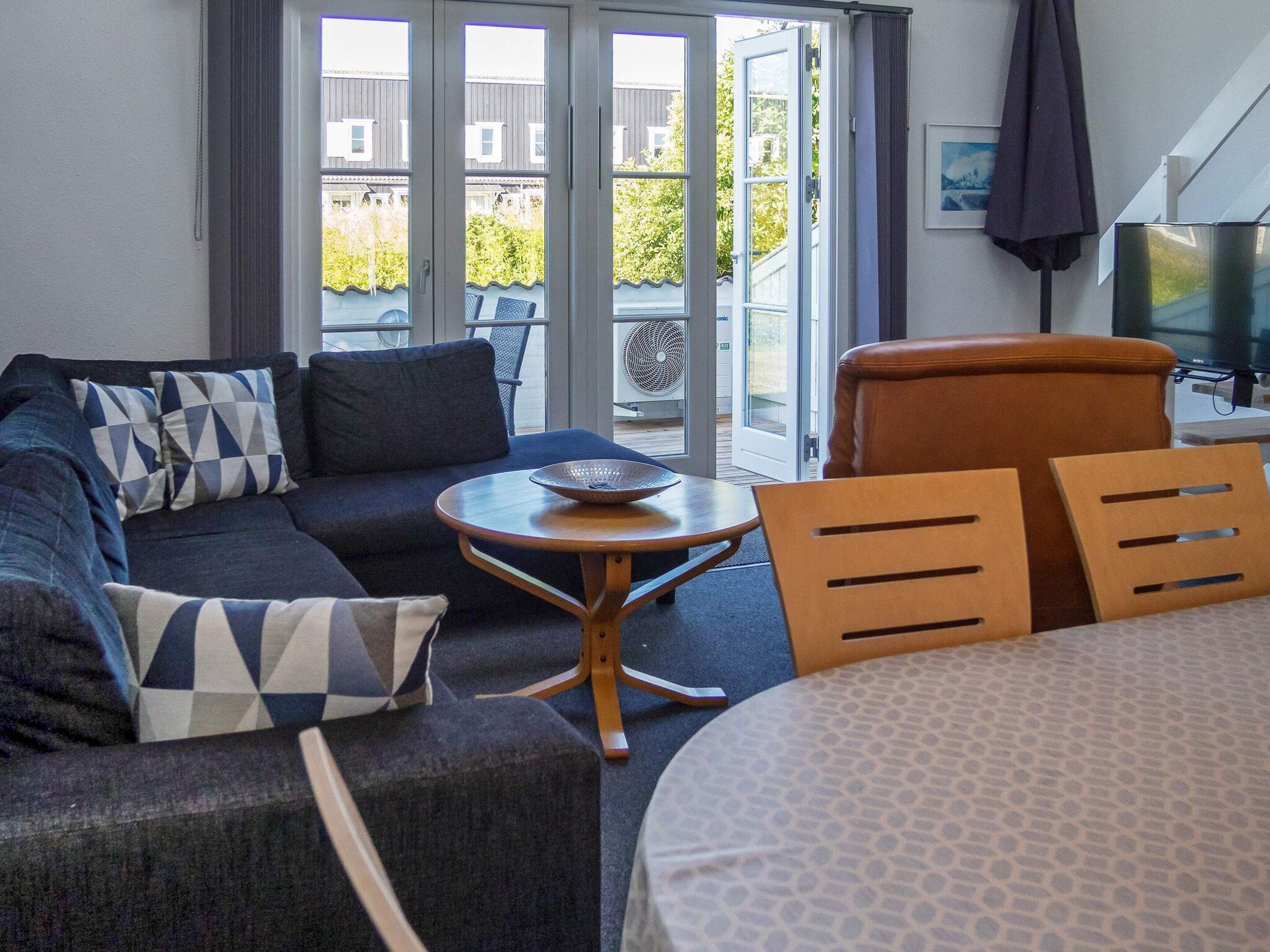 A hotel room with a sofa, a round table, a chair, a bed, and a TV.