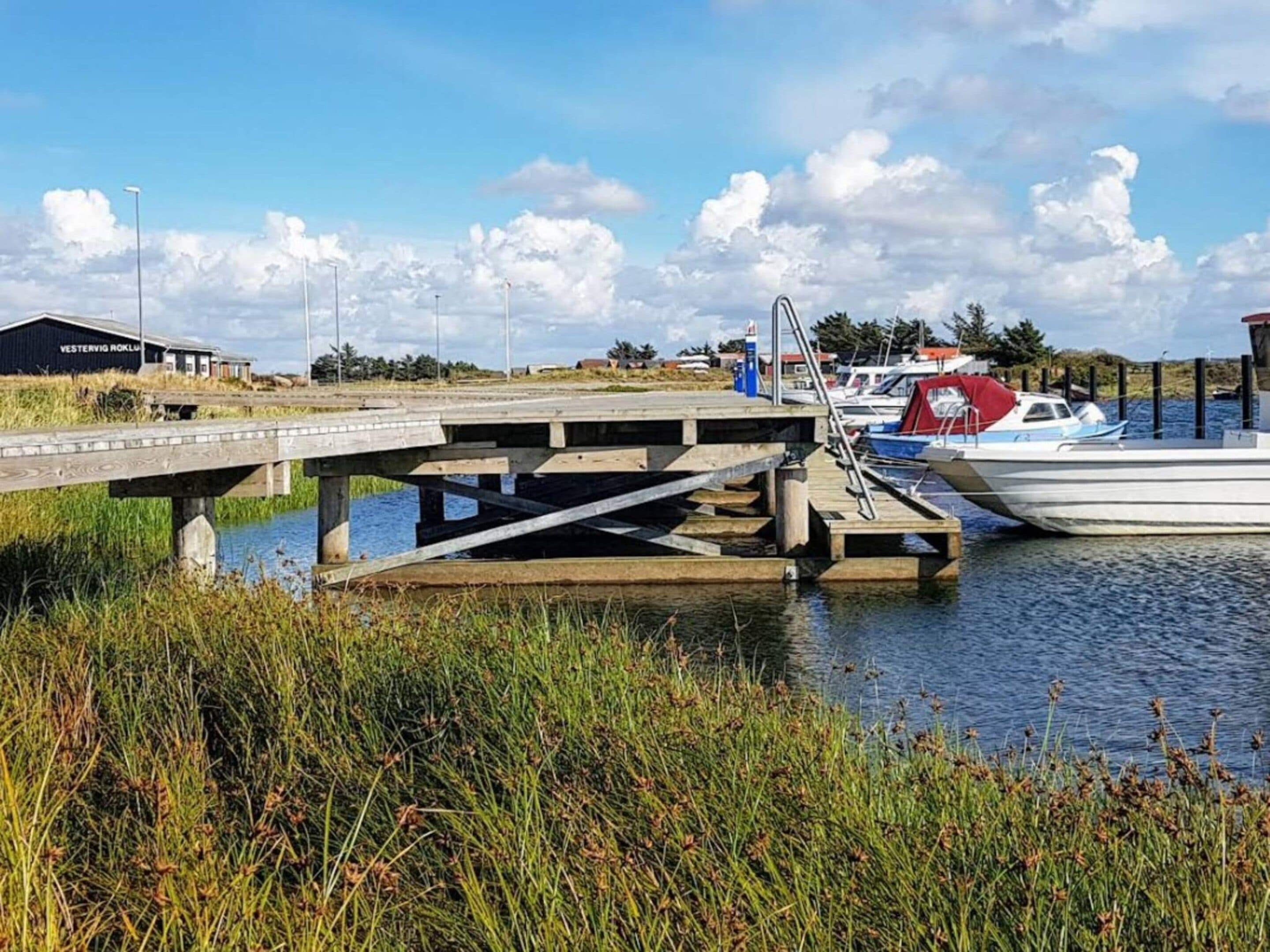 A bridge over water with boats docked, a building labeled 'VESTERVIG ROKKUL,' and grassy banks.