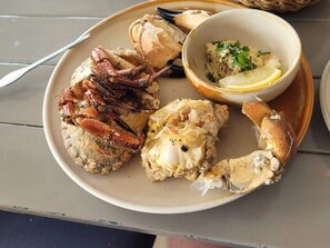 A plate with crab legs, a lobster tail, and a bowl of seafood salad. - 6 Person Holiday Home in Vestervig (Vestervig)