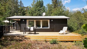 Eine kleine Hütte mit einer Terrasse, einem überdachten Sitzbereich und einer Satellitenschüssel.