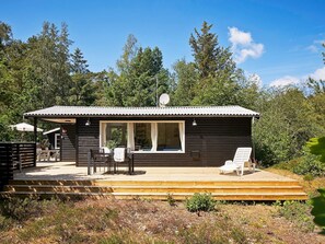 A small cabin with a deck, a covered seating area, and a satellite dish.