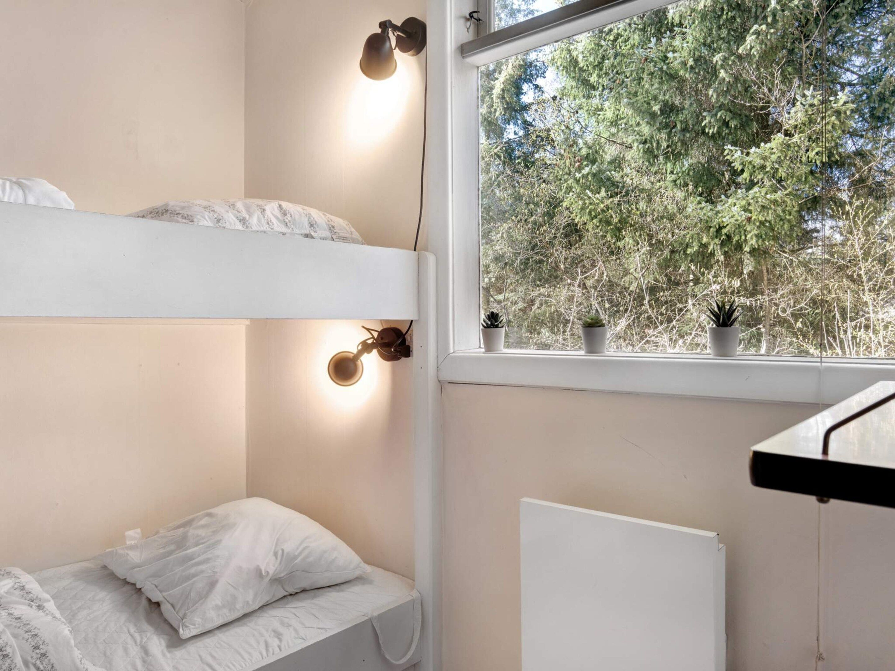 A bedroom with bunk beds, a window with a view of trees, and a radiator.