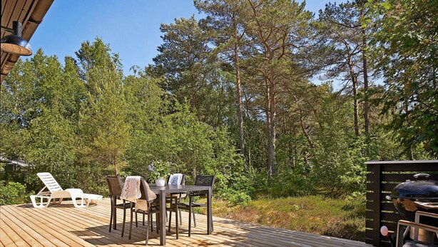 A wooden deck with outdoor furniture, surrounded by trees. - 8 Person Holiday Home in Nexo (Nexø)