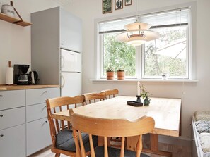 A compact kitchen with a dining table and chairs, a coffee maker, and a refrigerator. - 8 Person Holiday Home in Nexo (Nexø)