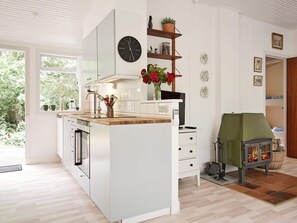 A modern kitchen with white cabinetry, a wooden countertop, a built-in stove, and a clock on the wall. - 8 Person Holiday Home in Nexo (Nexø)