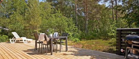 A wooden deck with outdoor furniture, surrounded by trees.