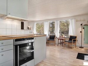 Een moderne keuken met een inbouwoven en een eethoek met een tafel en stoelen.