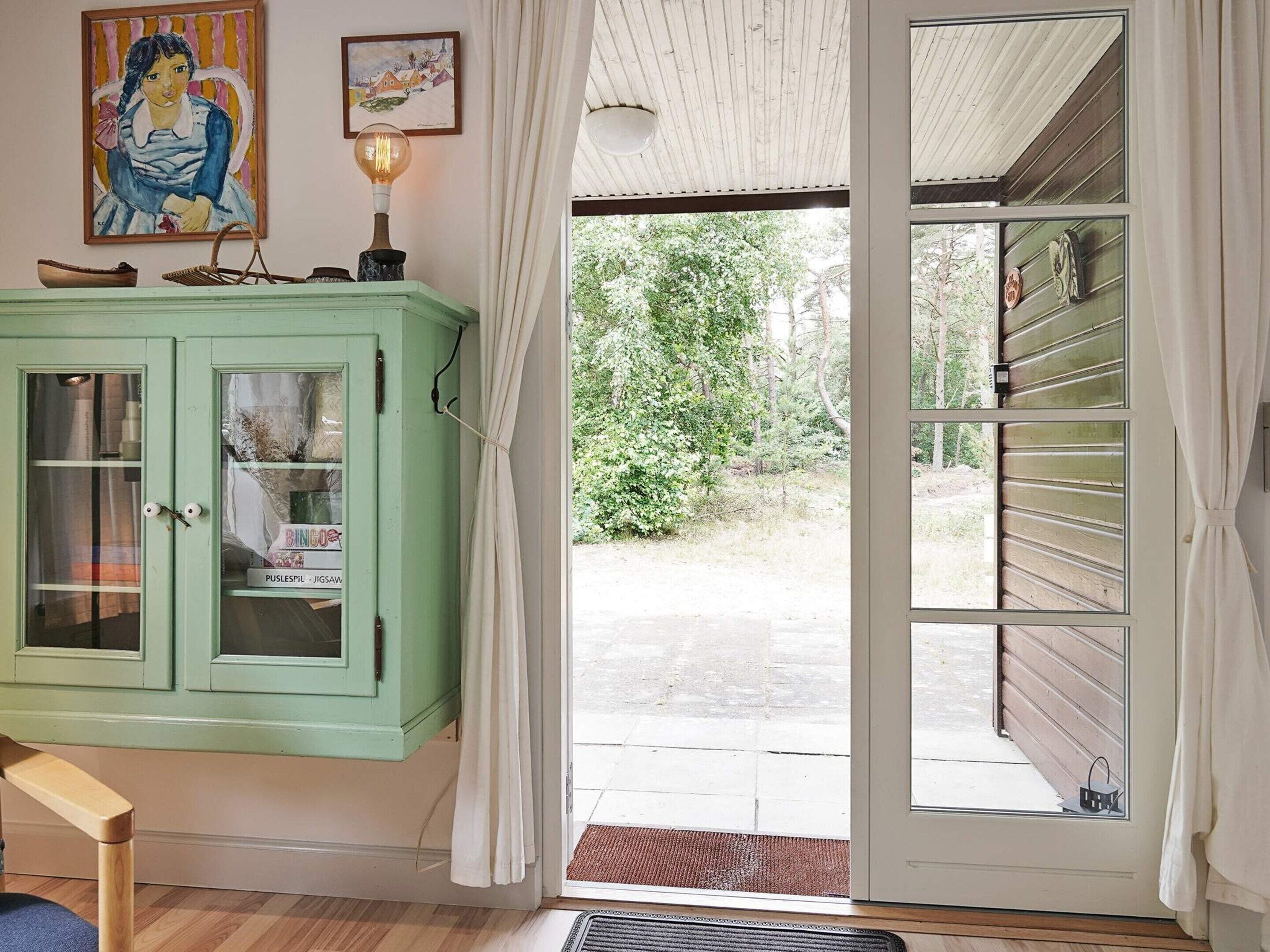 Una habitación con un armario verde, una puerta que da al exterior y una ventana con cortinas.