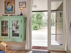 Une pièce avec un meuble vert, une porte donnant sur l’extérieur et une fenêtre avec des rideaux.