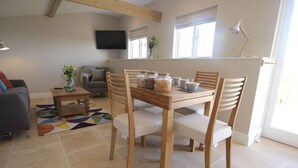 A dining area with a wooden table and chairs, a TV mounted on the wall, and a window with natural light. - Stunning location close to city centre - Pass the Keys (Bath)
