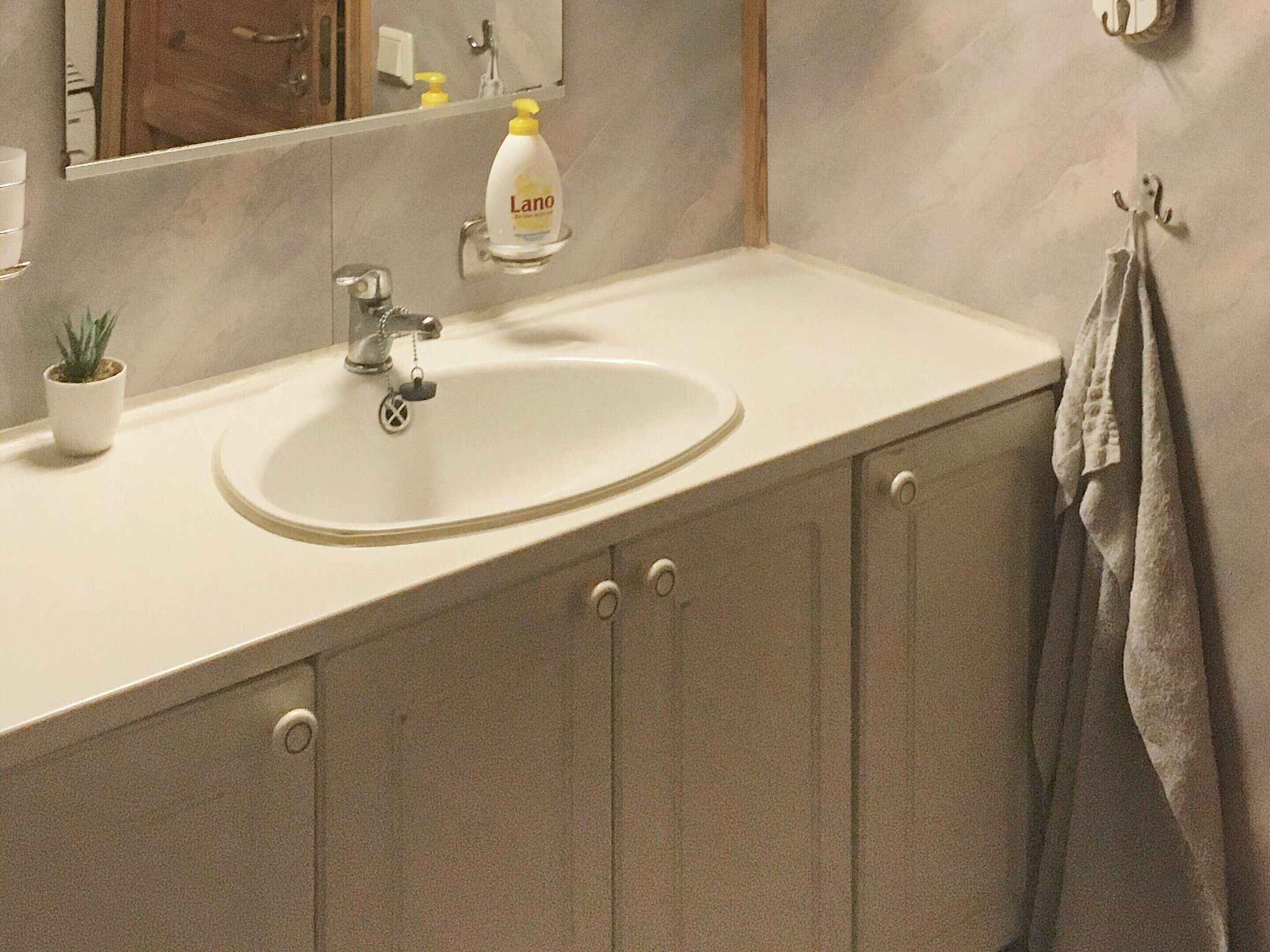 A bathroom with a sink, mirror, and towel rack.