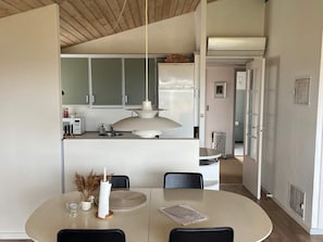Une cuisine moderne avec des meubles blancs, un îlot central et un luminaire suspendu.