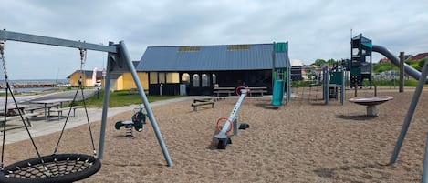 A playground with swings, a seesaw, and a slide.