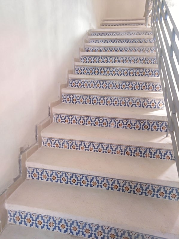 A staircase with patterned tiles and a metal railing.