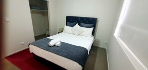 Relax in a cozy space with a neatly made bed and closet for your belongings.