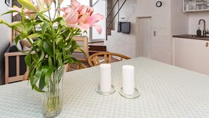 A dining area with a table set for two, a vase with flowers, and a kitchen in the background. - 4 Person Holiday Home in Brovst-by Traum (Brovst)