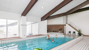 An indoor swimming pool with clear water, a tiled floor, and a brick wall in the background. - 4 Person Holiday Home in Brovst-by Traum (Brovst)
