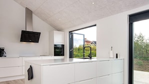 A modern kitchen with a large island, built-in oven, and a flat-screen TV. - 8 Person Holiday Home in Ebeltoft (Ebeltoft)