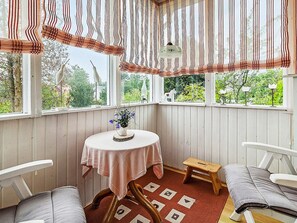 A cozy corner with a round table, two chairs, a small stool, and a view of greenery outside. - 4 Star Holiday Home in Bruzaholm (Bruzaholm)