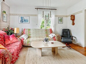 Ett vardagsrum med en soffa, ett soffbord, en fåtölj och en klocka på väggen.