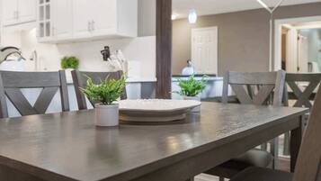 A dining area with a wooden table, two potted plants, and a white plate.