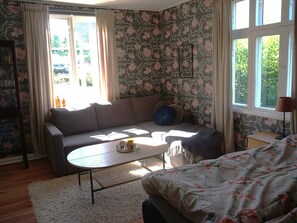 A room with a sofa, a coffee table, and a bed with floral bedding.
