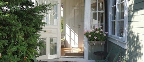 A wooden door leading to a porch with a bench and a potted plant.