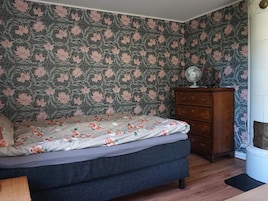 Un dormitorio con una cama, un aparador y una pared con estampado floral.
