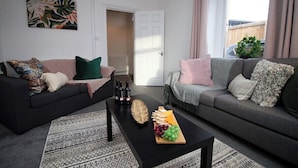 Ett vardagsrum med två soffor, ett soffbord med snacks och en dörr som leder till ett annat rum.